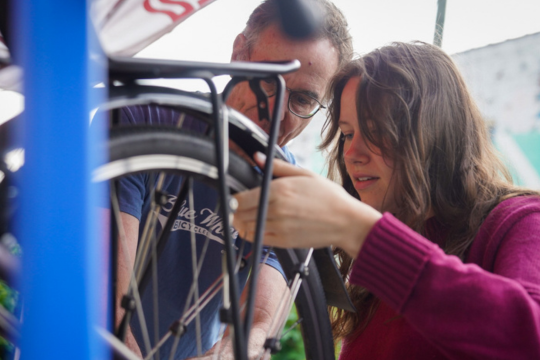 Two people shown working on a bike