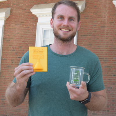 Noah Perry smiling with a beaker and gold certification