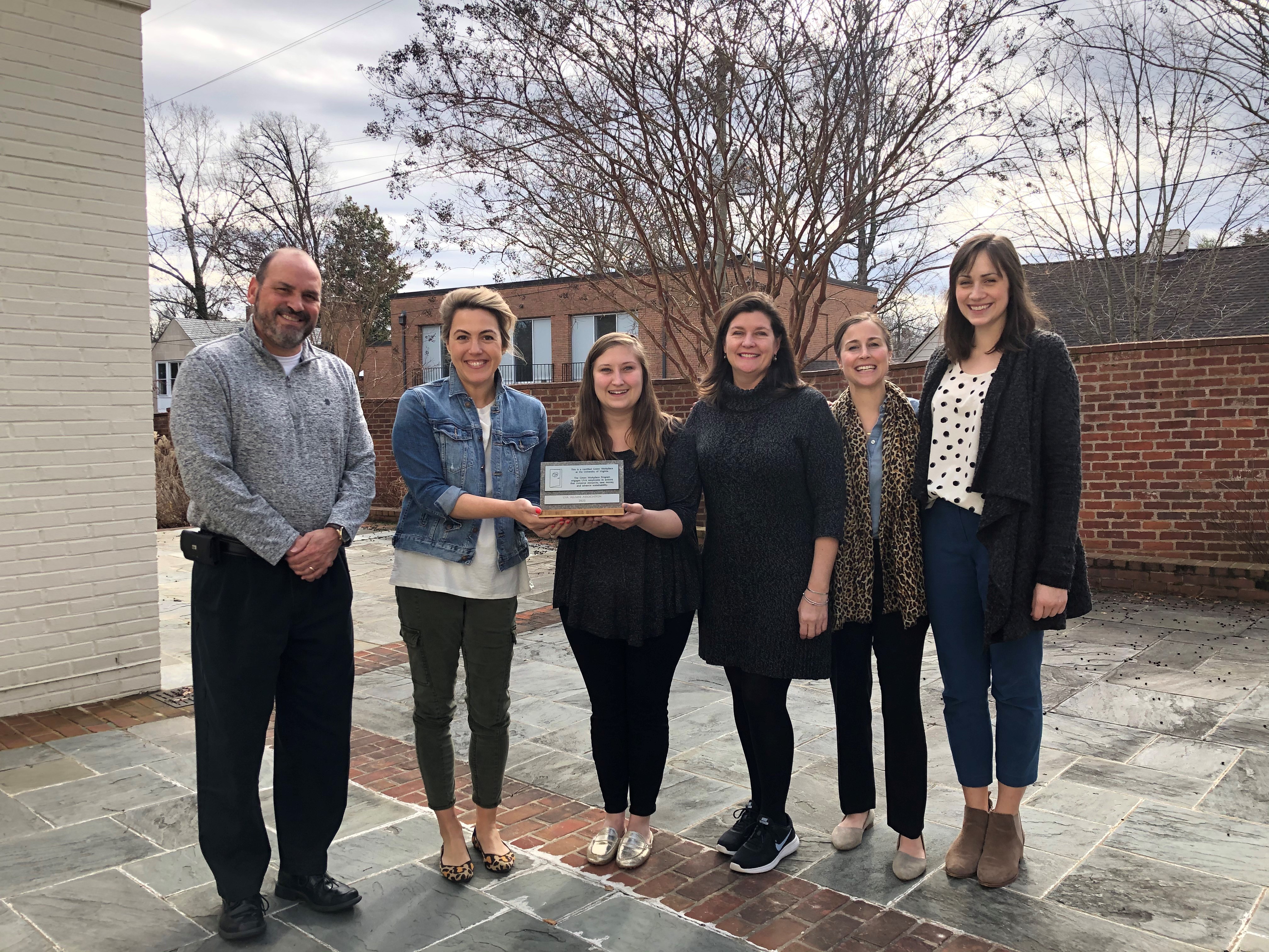 Six people standing with their Green Workplace plaque smiling outside their office