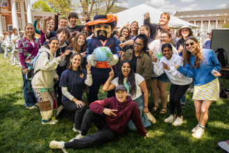 Students standing in a group smiling with cavman and globe