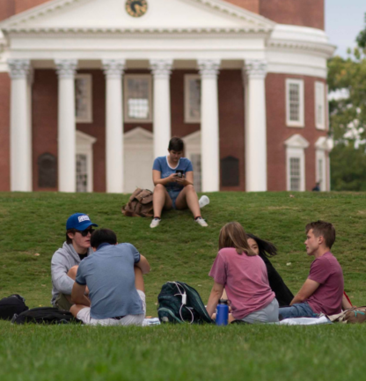 Students sitting in front of the Rotunda on the grass