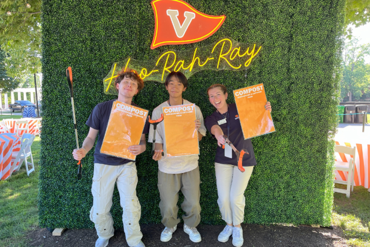 Three UVA students posing with compost signs and pickers.