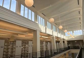 Top level of a library with a skylight, balcony, and bookshelves