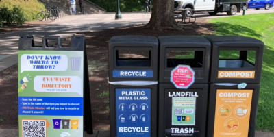 Image showing 3 waste stations side by side that are recycling, landfill, and compost. A sign next to them advertises for the UVA Waste Directory.