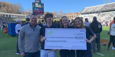 Three service learning team members accept a check from GFL on the field of Scott Stadium.
