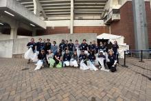 Student volunteers stand outside of Scott Stadium with trash pickers and bags