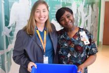 Alicia White and Tabatha Gilbert smile with a recycling bin