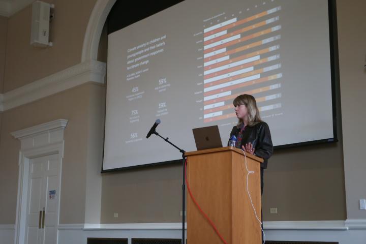Britt Wray at the Podium in front of a slide about the Lancet study referenced in the blog