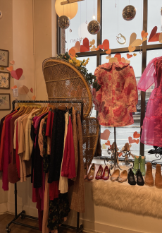 A photo of a clothing rack and window display with Valentine's Day decor. 